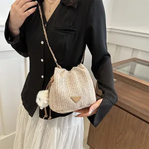 Detailed view of beige straw bucket bag featuring woven texture and chain strap