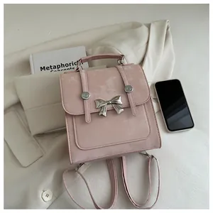 Detail shot of a pink leather backpack featuring a silver butterfly buckle on white clothing