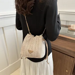 Detail of woven straw bucket bag with drawstring closure and metal chain strap