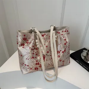 Detail of floral embroidery and pearl charm on a champagne tote bag surface