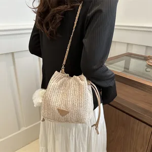Detail shot of a woven contrast bucket bag with gold chain strap worn over the shoulder