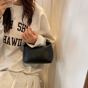 Detail of rich rabbit embossed lettering on black leather handbag held by model