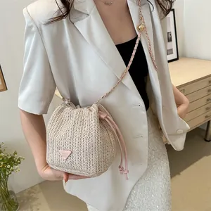 Detailed close-up of straw bucket bag featuring pink drawstring and chain shoulder strap