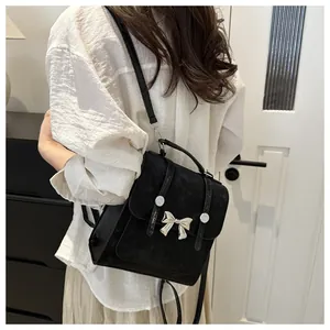 Detail of black crossbody bag with silver butterfly buckle and rivet straps on model