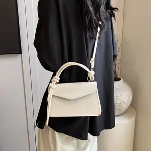 Gros plan du sac à main blanc texturé vintage avec détail de nœud et finitions dorées