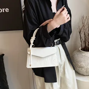 Détail d'un sac à main blanc en cuir PU texturé avec poignée nouée et ornements dorés élégants