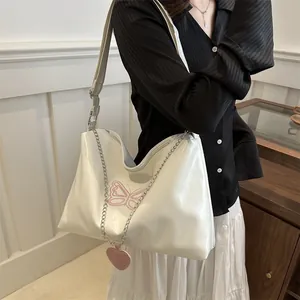 Close-up of white PU leather bag featuring pink butterfly embroidery and a heart pendant
