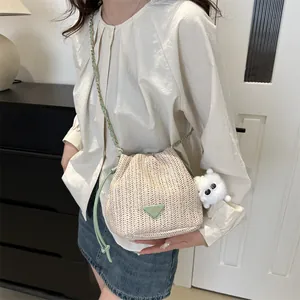 Straw bucket bag with mint green chain strap and bear charm shown on model