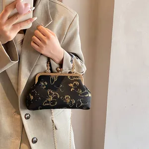 Detail of vintage black satin clutch with gold butterfly embroidery and metal chain strap