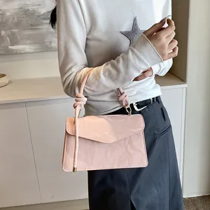 Détail du sac à main rose montrant la poignée nouée et le rabat brillant enveloppe