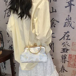 Detail of vintage kiss-lock bag with blue butterfly embroidery and golden chain strap