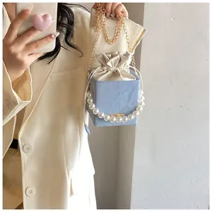 Light blue pleated bucket bag with pearl handle and gold chain strap on model
