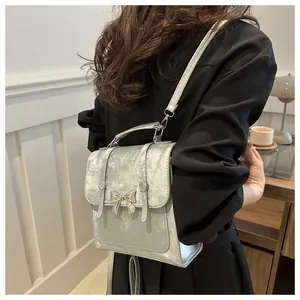 Detailed view of the silver metallic backpack featuring a decorative shiny metal bow