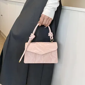 Détail d'un sac à bandoulière rose clair avec poignée nouée et finition en similicuir texturé