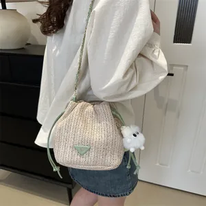 Detail of straw bucket bag with green drawstring and white plush bear pendant charm