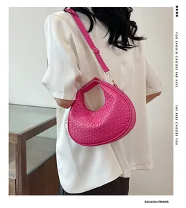 Close-up of hot pink crescent bag featuring woven texture and gold hardware details