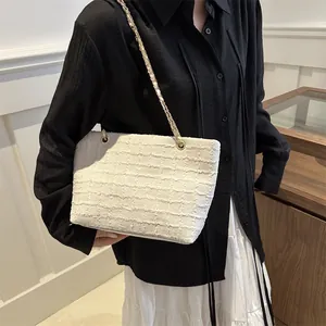 Detail of white tweed tote bag with gold chain strap shown on model's shoulder