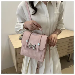 Pink suede-style handbag featuring a silver metal butterfly buckle and shoulder strap