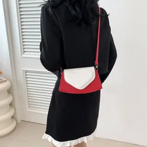 Detail view of the red and white heart-shaped flap on this stylish crossbody bag