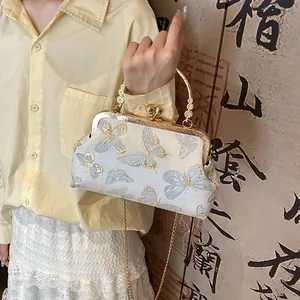 Close-up of vintage brocade handbag with light blue butterfly embroidery and metal clasp