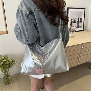 Silver shoulder bag with pink butterfly embroidery and heart charm on metal chain strap