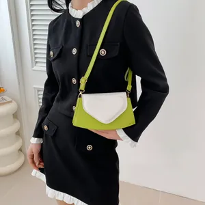 Detail of neon green heart-shaped crossbody bag with white accents and metallic chain
