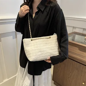 Detailed close-up of white tweed texture and gold chain strap on women shoulder bag