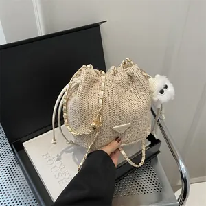 Detail of straw bucket bag with gold chain strap and fluffy charm in luxury setting