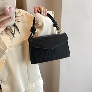 Détail de la texture en cuir noir froissé sur un petit sac avec poignée nouée