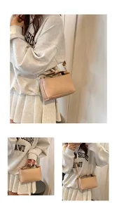 Detail of beige PU leather bag with embossed lettering and gold metal buckles