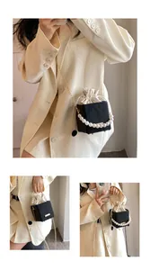 Detail of elegant two-tone bucket bag featuring pearl handle and gold chain strap