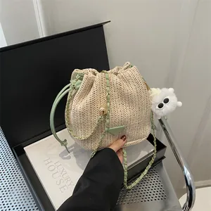 Detail of woven bucket bag with green leather trim and golden chain strap in luxury box