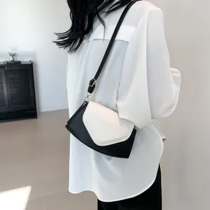 Detail of a black and white heart-shaped crossbody bag worn by a model from a side view