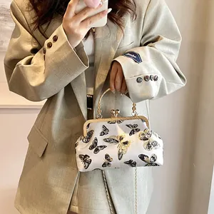 Detailed view of a vintage white embroidery bag with butterfly patterns and gold chain