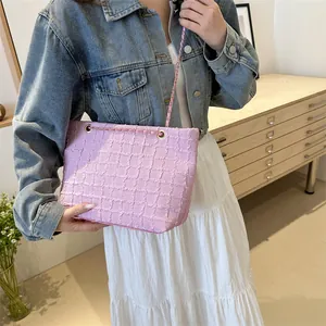 Close-up of pink woven texture tote bag with chain strap worn on woman's shoulder