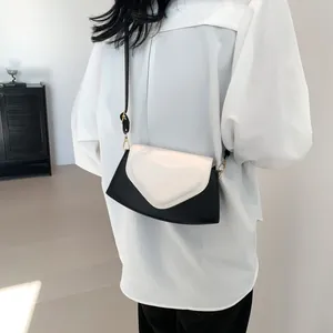 Detail of a chic black and white contrast crossbody bag with heart-shaped flap design