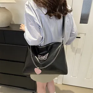 Close-up of black crossbody bag featuring pink butterfly embroidery and silver chain detail