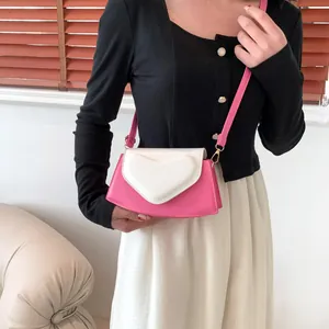 Pink and cream contrast crossbody bag with heart detail and gold hardware on model
