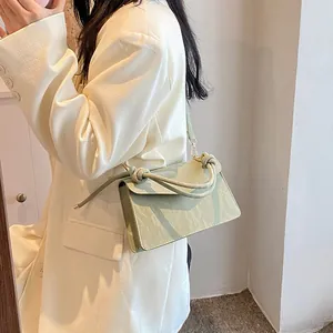 Sac à bandoulière en cuir plissé vert sauge avec poignée nouée sur un blazer blanc