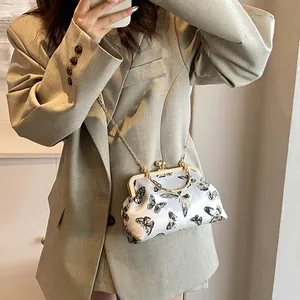 Detail view of a vintage light gray brocade bag with gold butterfly embroidery and chain strap
