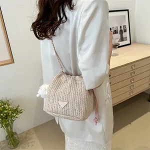 Straw bucket bag with contrast pink triangle logo and chain strap on female model