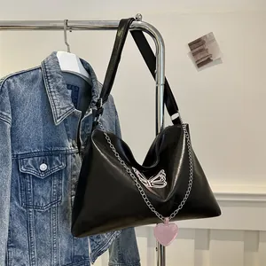 Close-up of black crossbody bag with pink butterfly embroidery and heart charm