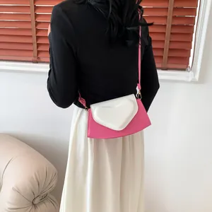 Detail of a pink and white crossbody bag with heart decoration worn by a model