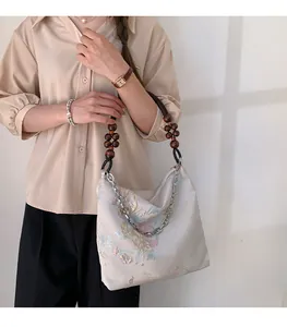 Detail of silk tote bag with floral embroidery, wooden beads and silver metal chain