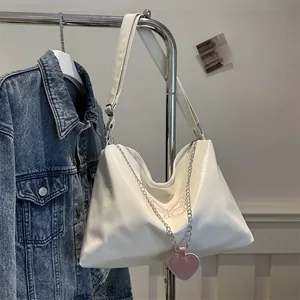 Detail of white PU shoulder bag with pink butterfly embroidery and heart charm