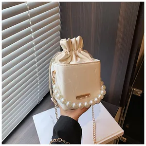 Detail of white marble textured bucket bag with pearl handle and golden chain strap