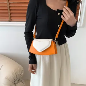 Detail of a chic orange and white contrast crossbody bag with heart ornament and strap
