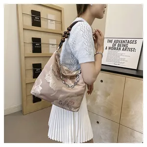 Detail of floral embroidery and wooden bead chain strap on silk shoulder tote bag