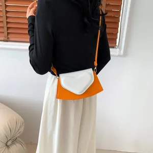 Detail shot of orange and white crossbody bag with heart flap on model's shoulder