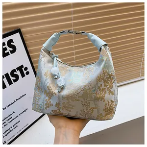 Detail of silk jacquard landscape pattern and pearl charm on a light blue handbag